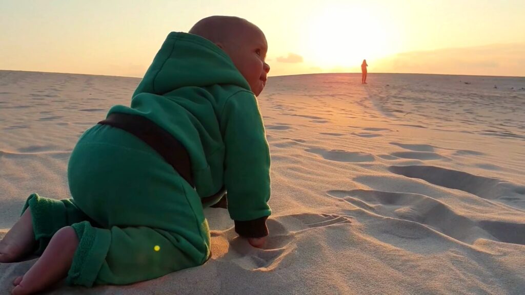 Kind bewegt sich im Sand bei Sonnenuntergang als Symbol für ursprüngliche Erfahrung, Entwicklung und bewusstes Menschsein